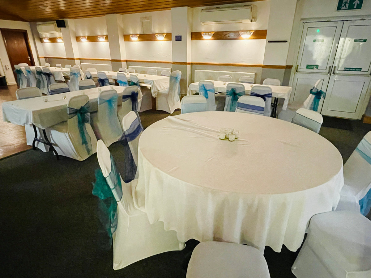 Round table with white linen and chair sashes ready for a celebration