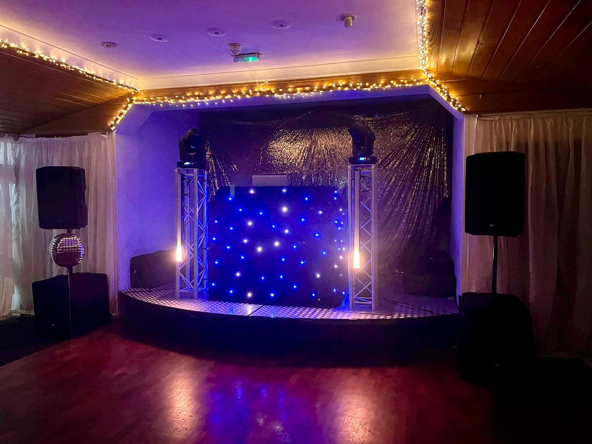 Stage and dance floor lit up for a party in the function hall