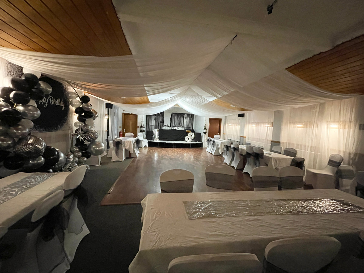 Hall dressed with ceiling drapes, balloons and covered chairs