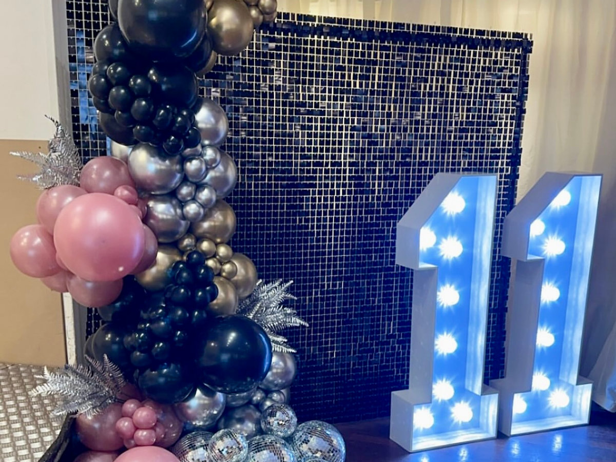 Sequin backdrop with balloon arch and illuminated numbers